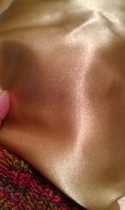 This is the gold shiny fabric I am considering using for the knitting needles.  I will mull it over.